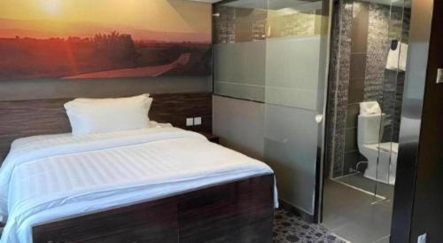 a bedroom with a bed with a painting on the wall at J Link Hotel in Hong Kong