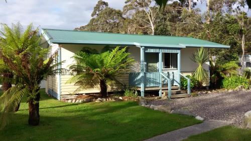 una pequeña casa amarilla con techo verde en Strahan Retreat Holiday Park, en Strahan