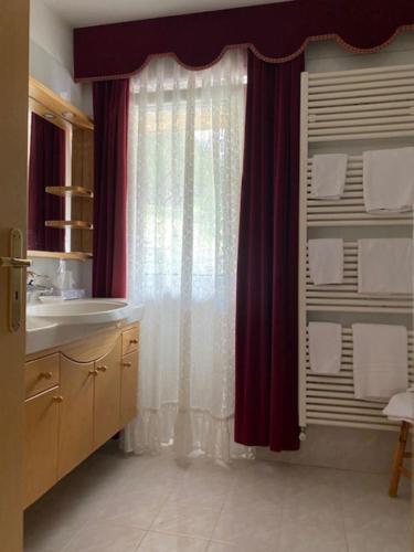 a bathroom with a sink and a window with curtains at Garni B&B Schenk in Selva di Val Gardena