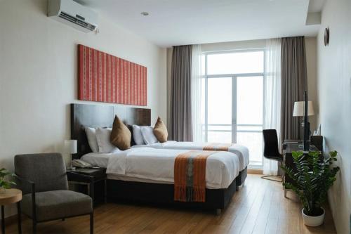 a bedroom with a bed and a chair and a window at Timor Plaza Hotel & Apartments in Dili