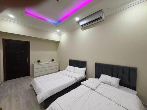 two beds in a room with purple lights on the ceiling at darnas in Jeddah