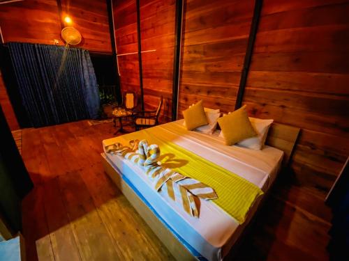 a large bed in a room with wooden walls at Senaro Villa in Sigiriya