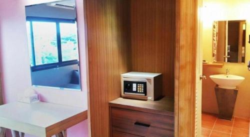 a bathroom with a microwave on a counter with a sink at Klim Hotel in Buriram