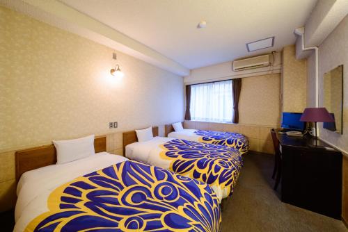 a hotel room with two beds and a desk at Kyoto Travellers Inn in Kyoto