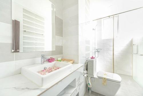 a white bathroom with a sink and a toilet at Queen Mansion Hotel & Stays in Phnom Penh