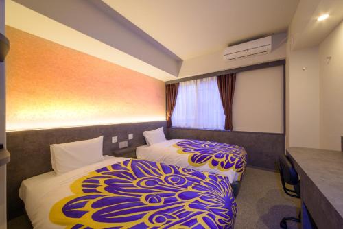 a hotel room with two beds and a window at Kyoto Travellers Inn in Kyoto