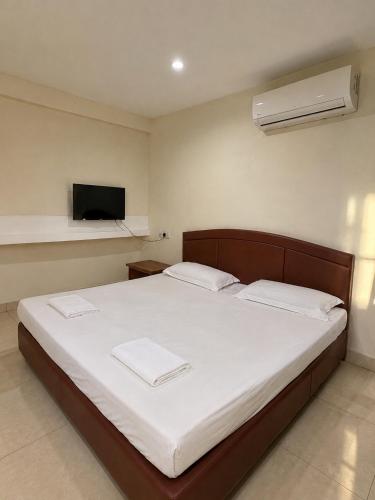 a bedroom with a bed with white sheets and a television at HK Inn Hua Kiew Inn in Miri