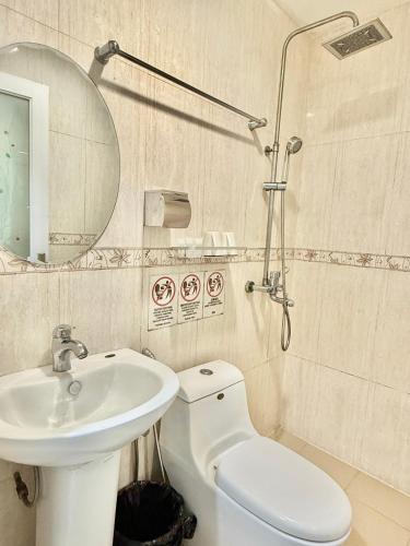 a bathroom with a sink and a toilet and a mirror at HK Inn Hua Kiew Inn in Miri