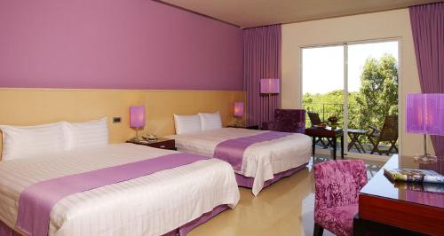 two beds in a hotel room with purple walls at Papago International Resort in Chishang