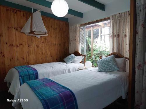 a bedroom with two beds and a window at Alba the Scots Cottage walk every where in Maleny
