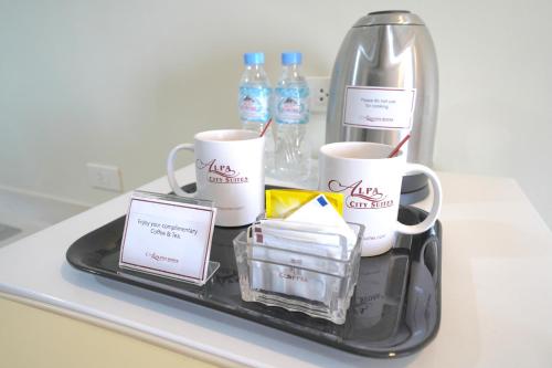 a tray with three coffee mugs and bottles of water at Alpa City Suites Hotel in Cebu City