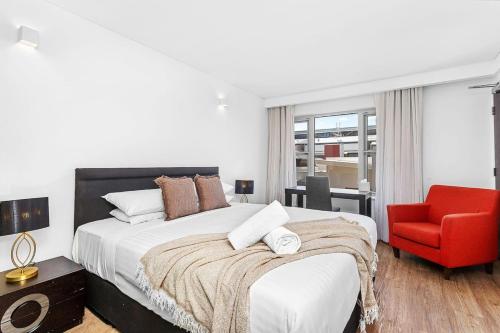 a bedroom with a bed and a red chair at Nest on Newcastle - E3 in Perth