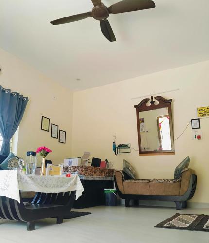 a living room with two chairs and a ceiling fan at Drizzle Home - A Cosy Stay in Yercaud