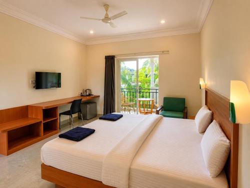 a bedroom with a bed and a desk and a window at Morjim Sunset Guesthouse- Apartments with Kitchen & AC Rooms in Morjim
