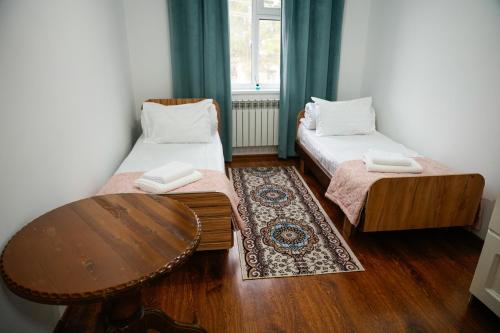 a small room with two beds and a table at Meyman House in Karakol