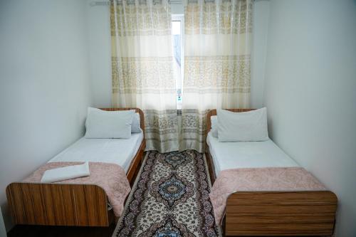 two beds in a room with a window at Meyman House in Karakol