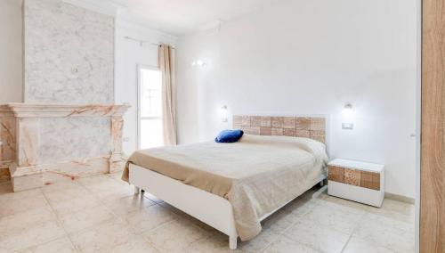 a white bedroom with a bed and a fireplace at Villa Blu Dea room & apartment in Torre Lapillo