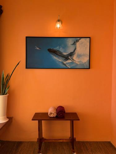 an orange wall with a table and a picture of a whale at Summer Beach House in Alleppey