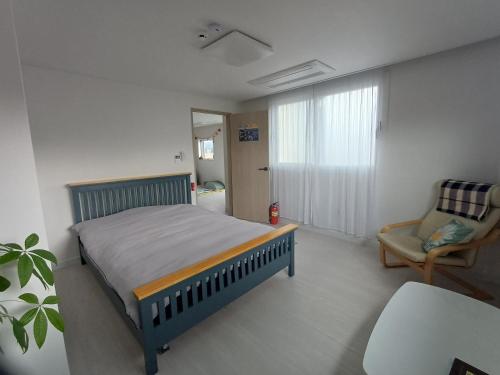 a bedroom with a bed and a chair and a window at The upper room디어퍼룸 in Mahŭl-tong