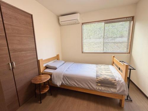 a small bedroom with a bed and a window at Oyado SORARURI in Yakushima
