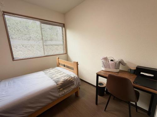 a bedroom with a bed and a desk and a window at Oyado SORARURI in Yakushima