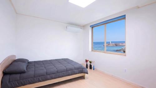 a bedroom with a bed and a large window at Samcheok Jisu Pension in Samcheok