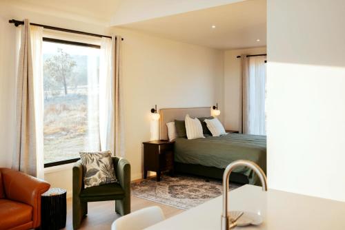 a bedroom with a bed and a chair and a window at Glenbosch - Cottage One in Beechworth