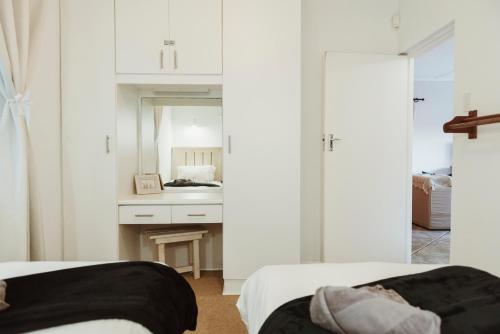 a bedroom with two beds and a desk with a mirror at Wildecrest & Ripplemead, Amblewood Guesthouse in Kenton on Sea
