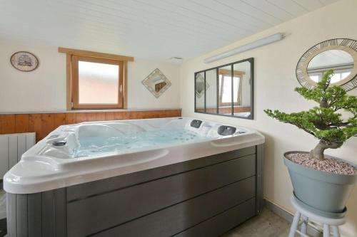 a bathroom with a large tub with a potted tree at Gîte du Pont d 'Amourette in Mayenne