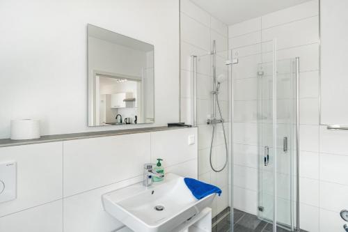 a white bathroom with a sink and a shower at Haus Seeluft - W3 in Butjadingen