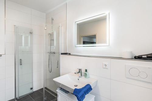 a white bathroom with a sink and a mirror at Haus Seeluft - W1 in Butjadingen