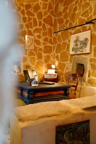 a desk in a room with a stone wall at Tenuta Bellassai in SantʼAlessio Siculo