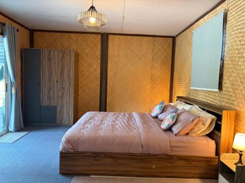 a bedroom with a bed with pillows on it at Alisa Villa, Ubon Cottage in Ban Pla Duk