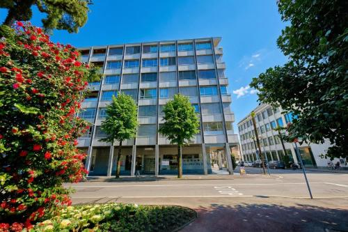 a tall glass building with trees in front of it at Casa Cupido Locarno - Happy Rentals in Locarno