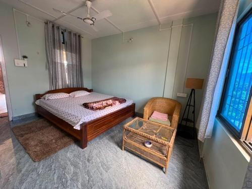 a bedroom with a bed and a chair and a window at BeeHive Homestay in Hāflong