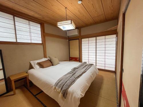 a bedroom with a bed in a room with windows at Tani House Tokiwa Nozawa Onsen & More in Iiyama