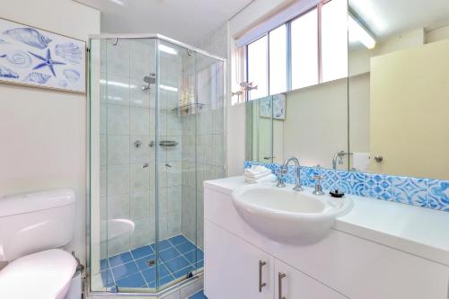 a white bathroom with a sink and a shower at Cullen Bay Resorts in Darwin