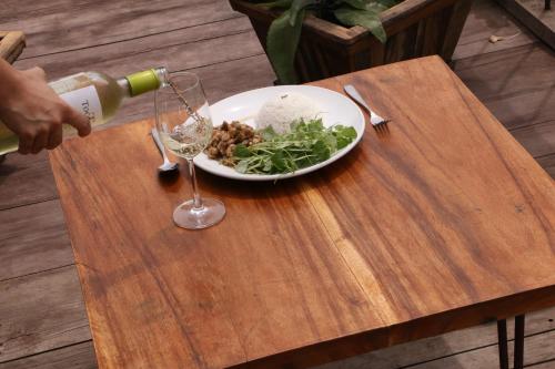 a plate of food and a glass of wine on a wooden table at ST 63 Home Stay & Tour Kampong Khleang in Kâmpóng Khleăng