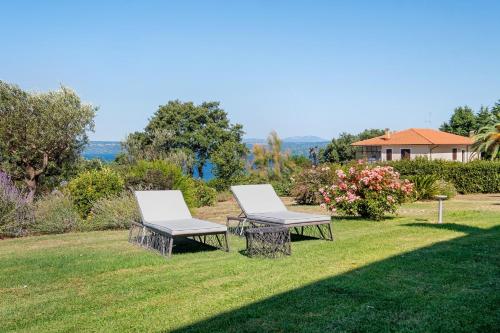 two white chairs sitting on the grass in a yard at Luxury Apartment Lake View in Bolsena