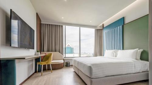 a bedroom with a bed and a desk with a chair at The Quarter Ratchayothin by UHG in Bangkok