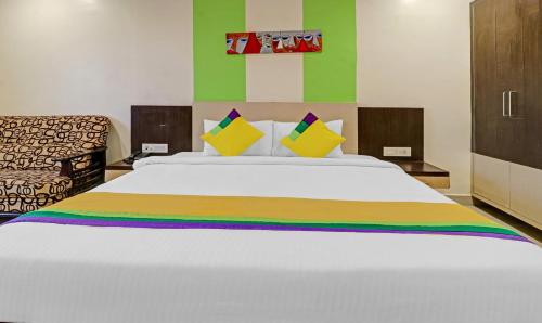 a bedroom with a large white bed with colorful pillows at Hotel G Square in Vijayawāda