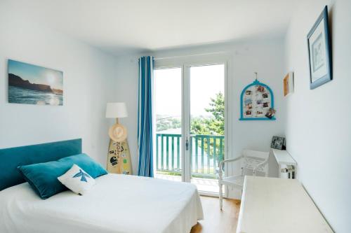 a white bedroom with a bed and a balcony at Maison basque familiale Eguski Alde in Saint-Jean-de-Luz