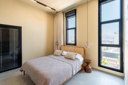 a bedroom with a bed and two large windows at Villa Lum - BY Harim in Eilat