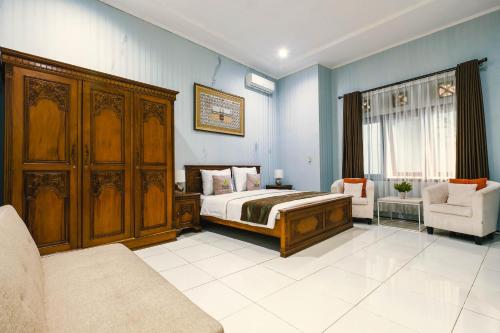 a bedroom with a bed and a couch and a chair at Aleyra Hotel and Villa's Garut in Garut