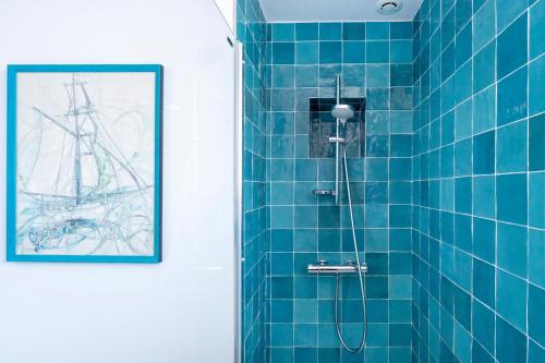 a bathroom with a blue tiled shower with a picture at Maison basque familiale Eguski Alde in Saint-Jean-de-Luz