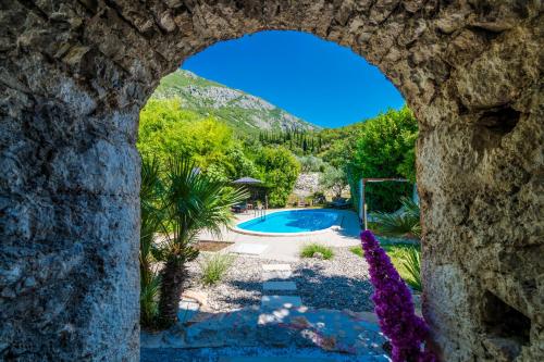 a view of a pool through a stone archway at Villa Balic in Gruda