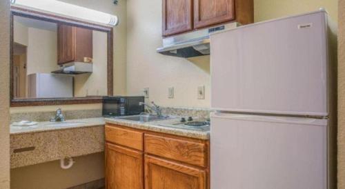 a kitchen with a white refrigerator and wooden cabinets at Rodeway Inn & Suites in Lakeview