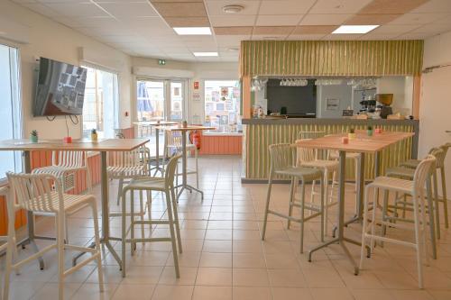 a restaurant with tables and chairs in a room at Camping Domaine du Morbihan in Ambon