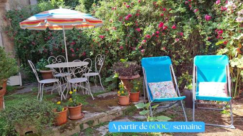 a table and chairs and an umbrella in a garden at Jardin et Hotel Particulier in Bayeux