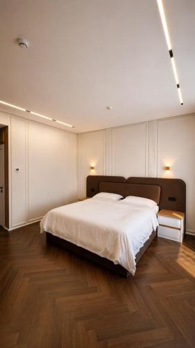 a bedroom with a large white bed and wooden floors at Hotel Zerbulaq in Taraz